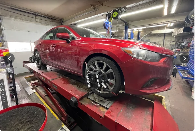 Red Mazda on alignment rack